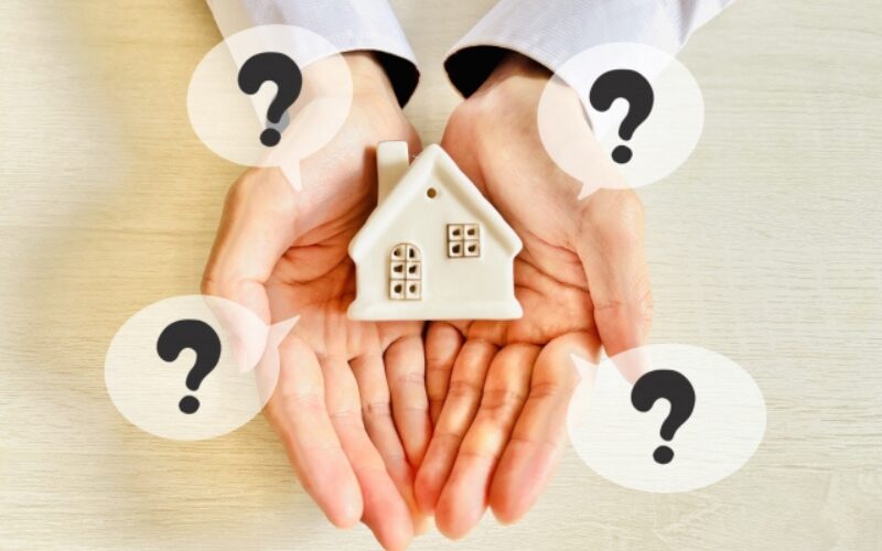 不動産売買契約に関するよくある質問を象徴する、手のひらの上の家の模型と疑問符