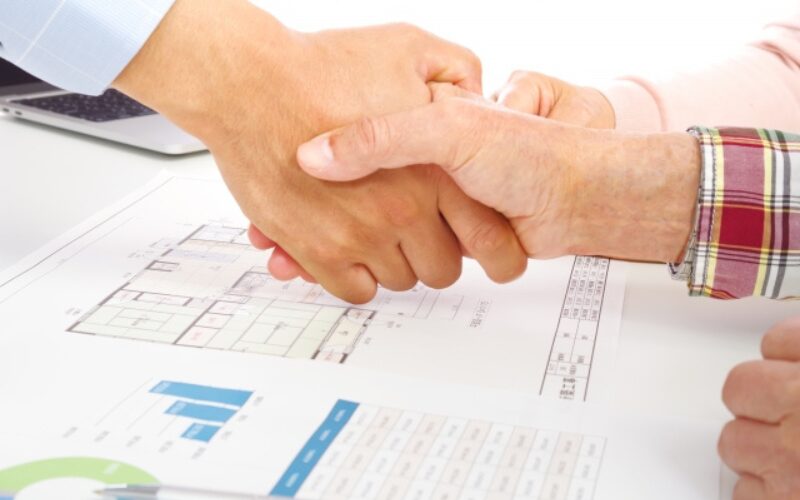 不動産売買契約が成立し、後悔しないための準備が完了したことを確認し合う握手の瞬間