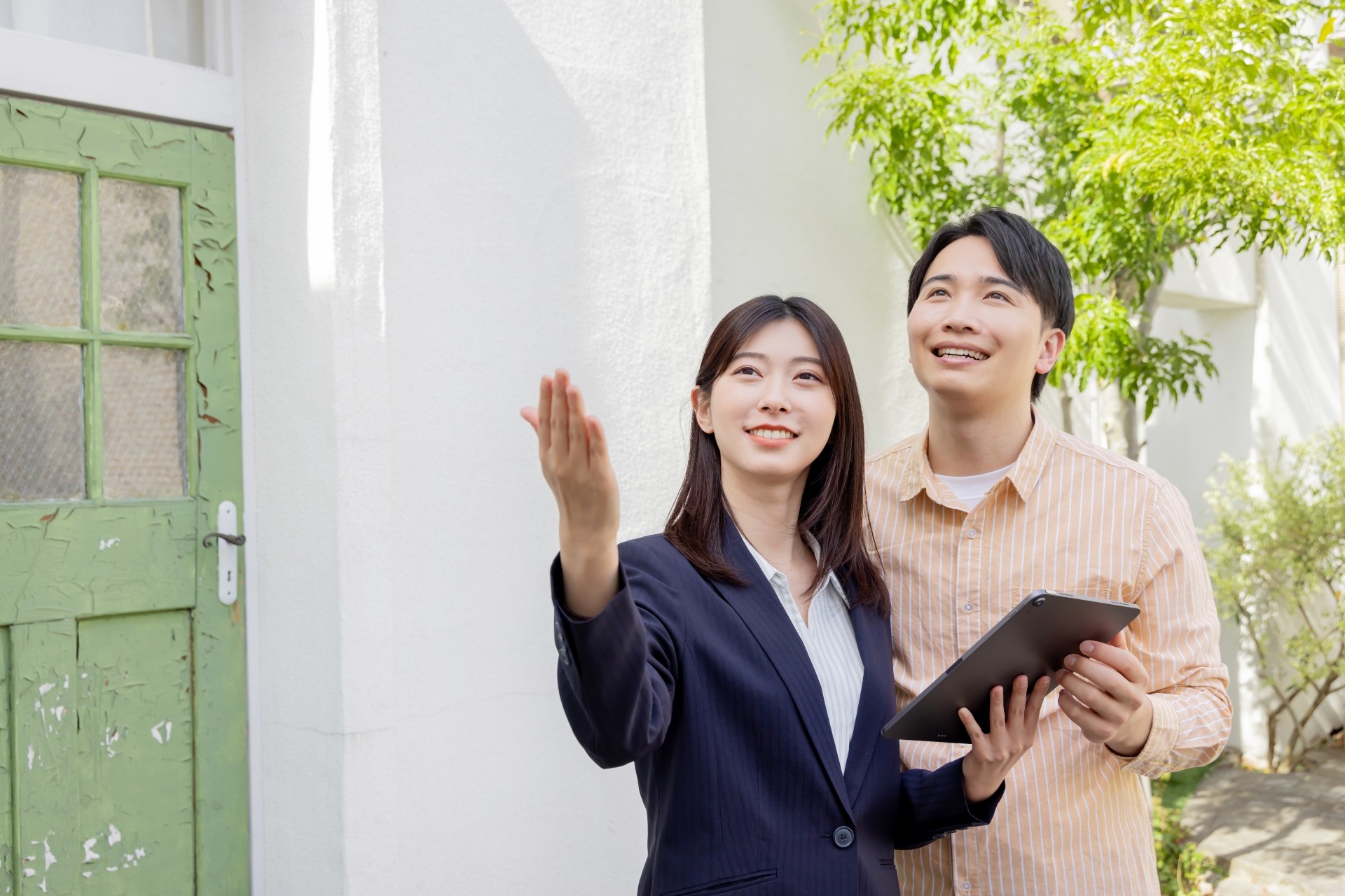 不動産会社担当者がタブレットを使い、家の売却相場を決める立地や環境を顧客に説明する