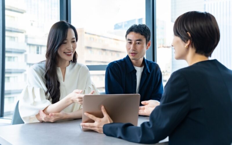 不動産売買に関する注意点や流れを、担当者から説明を受けている若い夫婦の様子