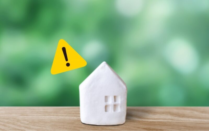 不動産売買契約における後悔しないための注意点やリスクを示す、警告マークと白い家の模型