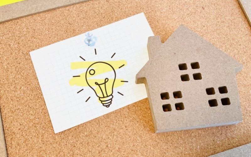家を売る最適なタイミングや、高く売るための工夫・ひらめきを表す電球のイラストと家のミニチュア