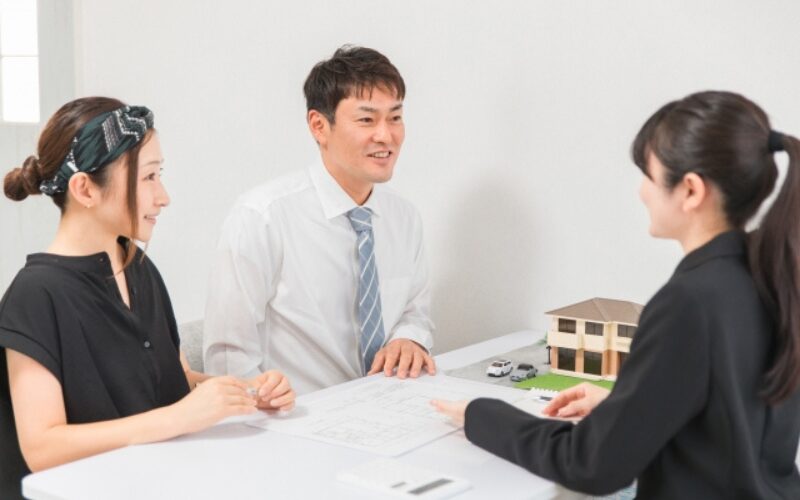 住み替えで家が売れない時の売却方法について、不動産担当者が夫婦に対処法を提案する打ち合わせの様子