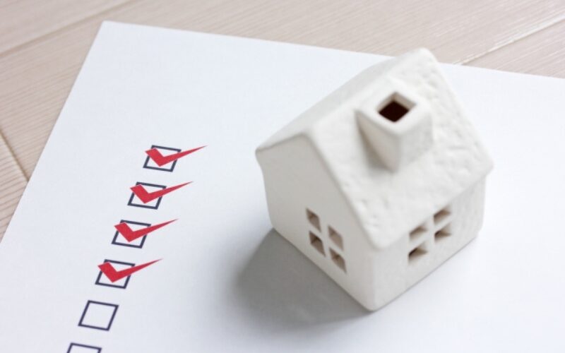 高く家を売るための判断要素をチェックする、チェックリストと戸建て住宅の白いミニチュア