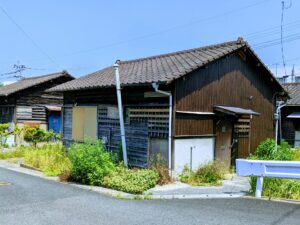 道路沿いに建つ、外壁が古びた木造の平屋の空き家。処分・活用方法が問われる