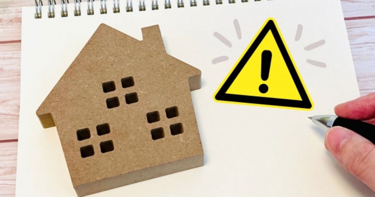 スケッチブック上の家の形のボードの横に描かれた、黄色い三角の注意喚起マーク