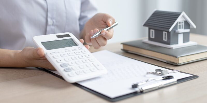 施設に入った親の家を売却する際の手続きや諸費用の計算に使う電卓と家の模型