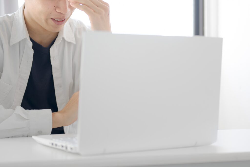 実家の売却手続きや相場調査に悩み、パソコンの前で頭を抱えて後悔する男性