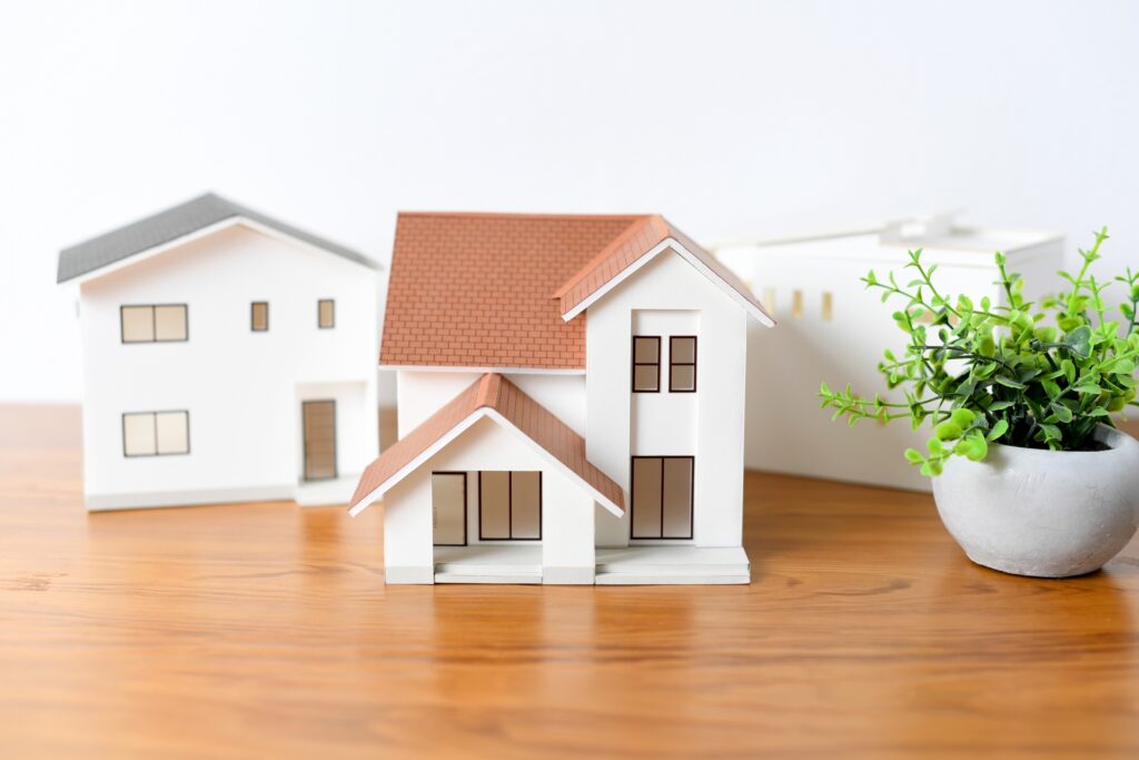 木製デスク上の注文住宅の模型と観葉植物。中古注文住宅の需要や市場価値の高まりを表現