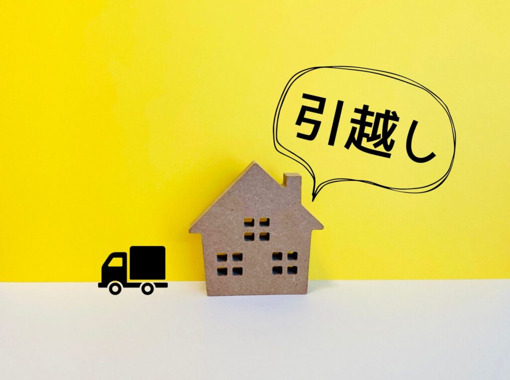 黄色い背景の手前に茶色い家の模型と黒いトラックのシルエット、「引越し」の文字の吹き出しがある