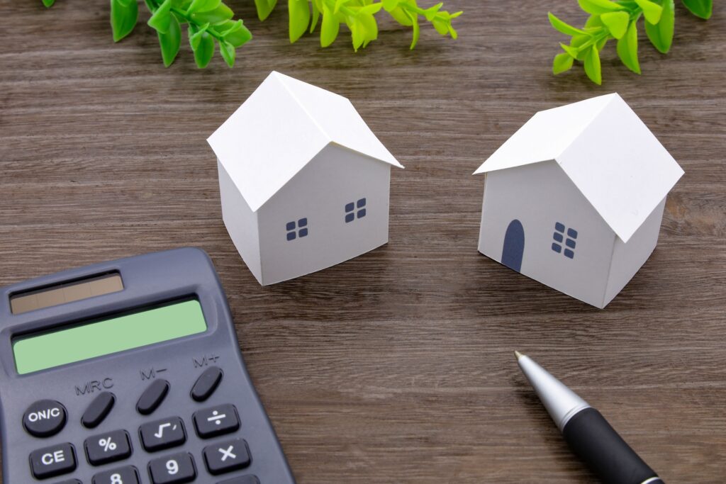 一戸建てと集合住宅の模型を並べ、住宅ローンの残債や財産分与を計算し査定する様子