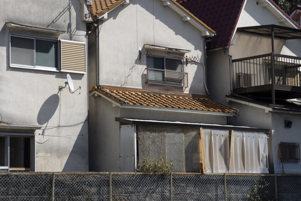 日本の住宅が密集する地域にある、瓦屋根やベランダを備えた空き家の壁面