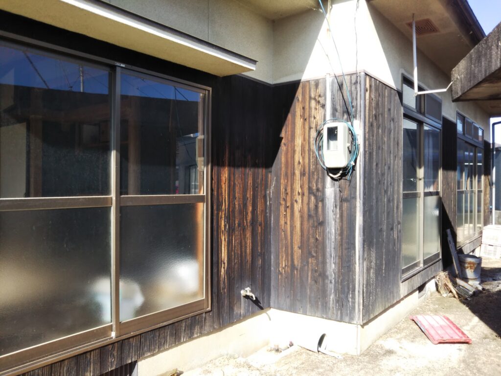 壁が黒くすすけた古い空き家。