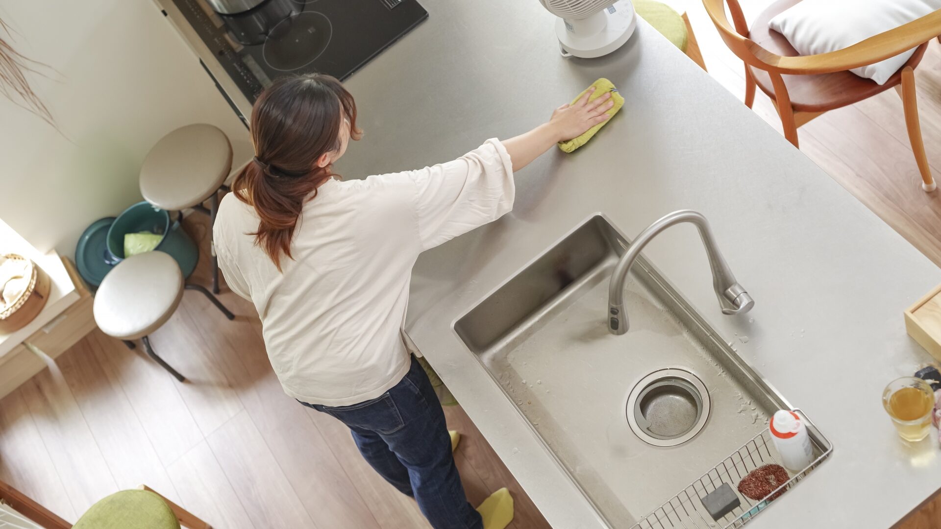 上から見たアングルで、女性がキッチンカウンターを拭き掃除している様子