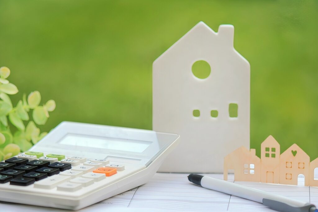 空き家売却や活用にかかる税金や費用を計算する電卓と家型の模型