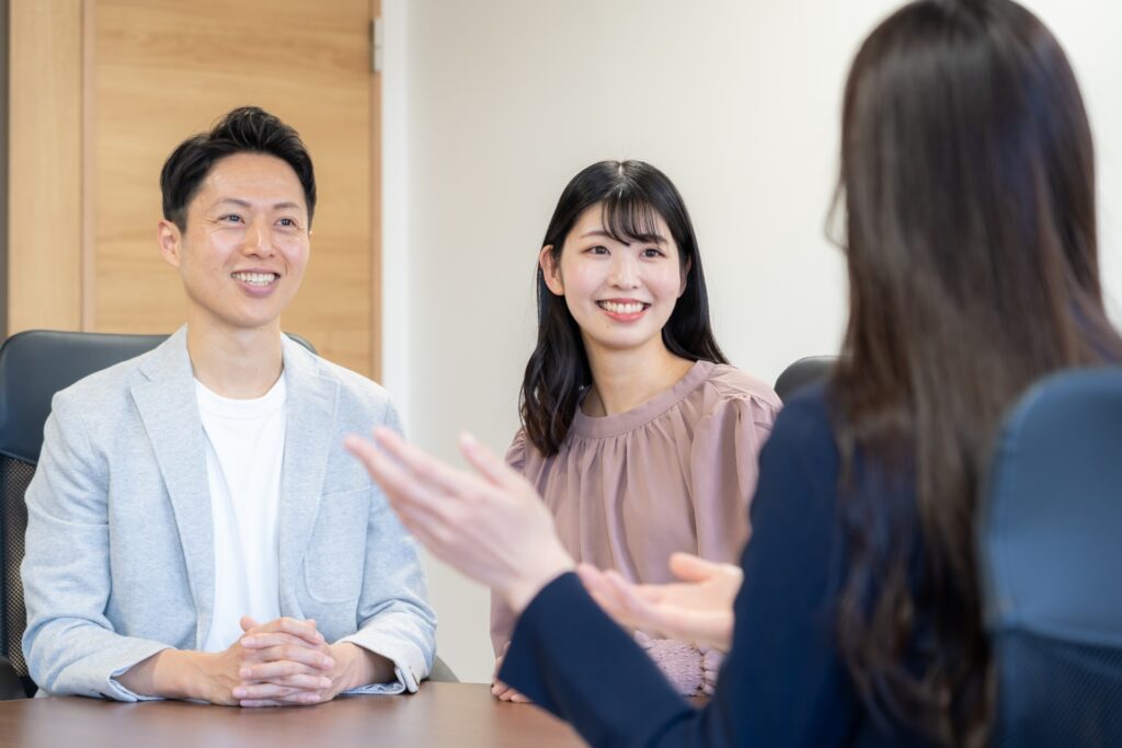 古い家を売る方法について、不動産会社で相談している笑顔の夫婦。売却のヒアリング