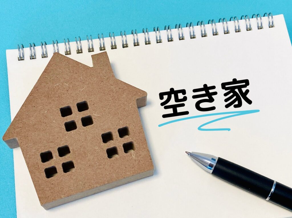 ノートに書かれた「空き家」の文字と家型模型。空き家問題や処分方法の検討