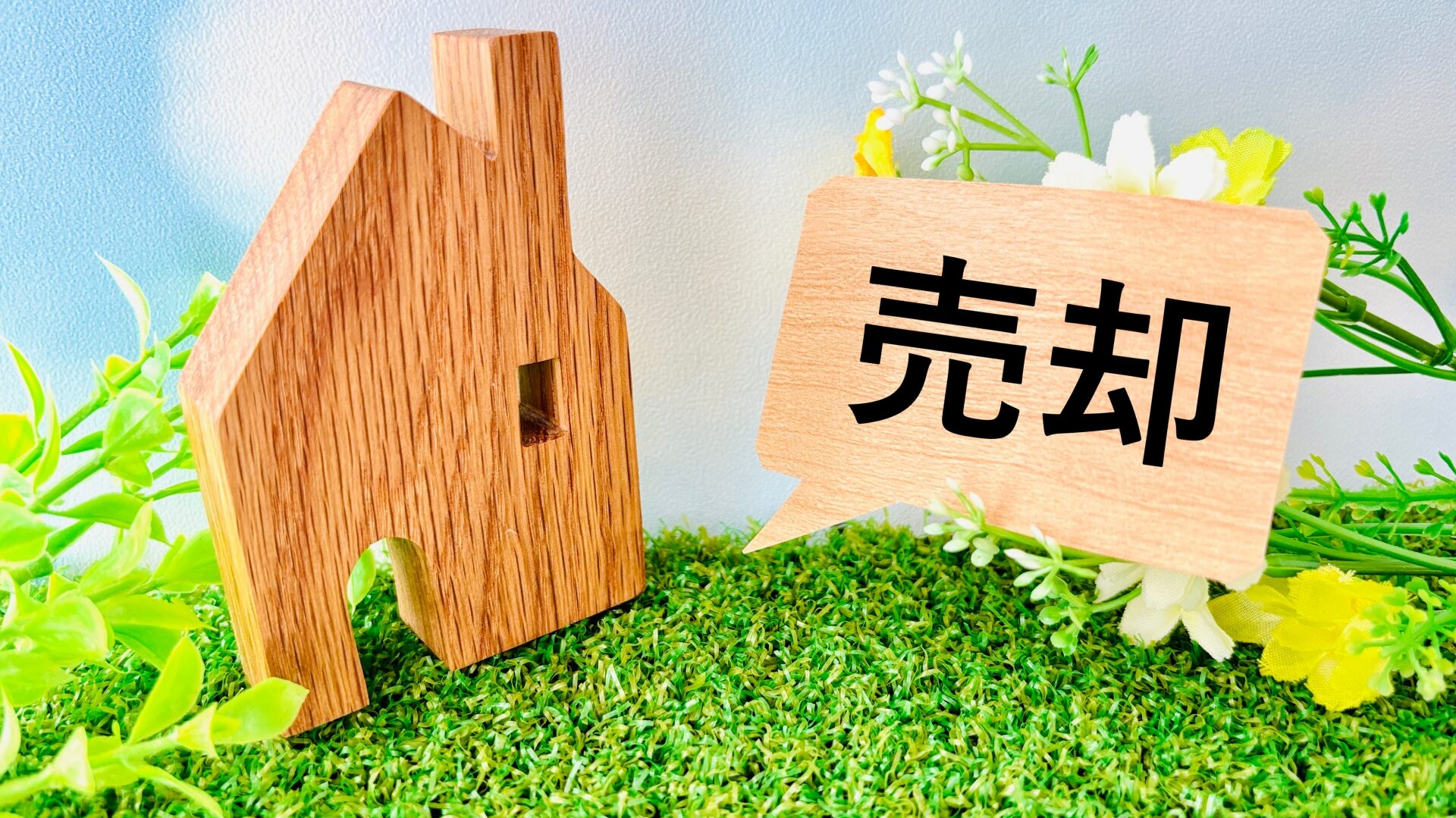 「売却」の文字が刻まれた木製ブロックと家の模型。