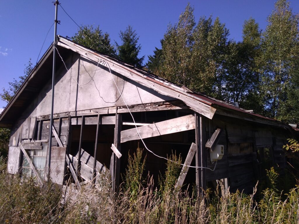 老朽化が激しく壁が崩壊した空き家の側面、処分や解体が必要な状態