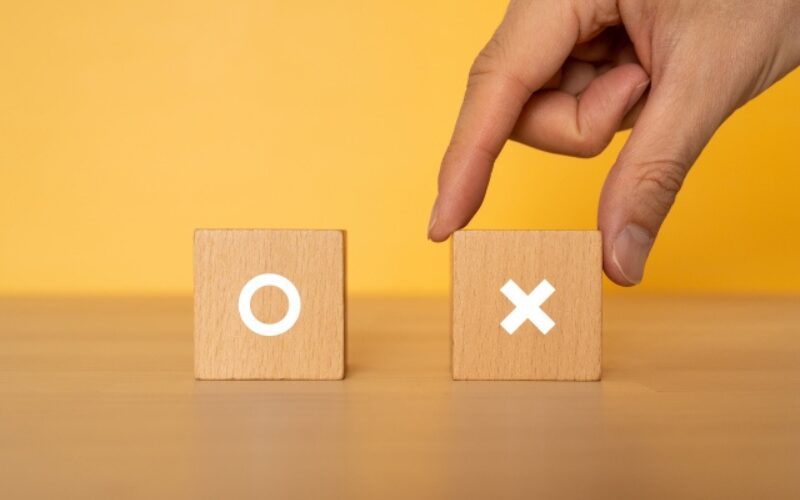 家を売る最適なタイミングや売却の判断要素の可否を決定する、「〇」と「×」の木製キューブ