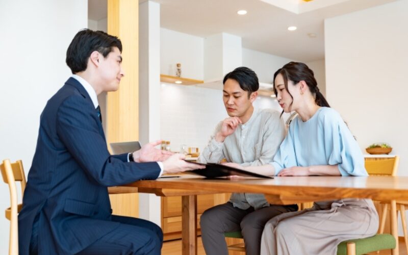 家が売れない状況で売却の対処法として信頼できる不動産会社の担当者が住み替え希望の夫婦と商談する様子