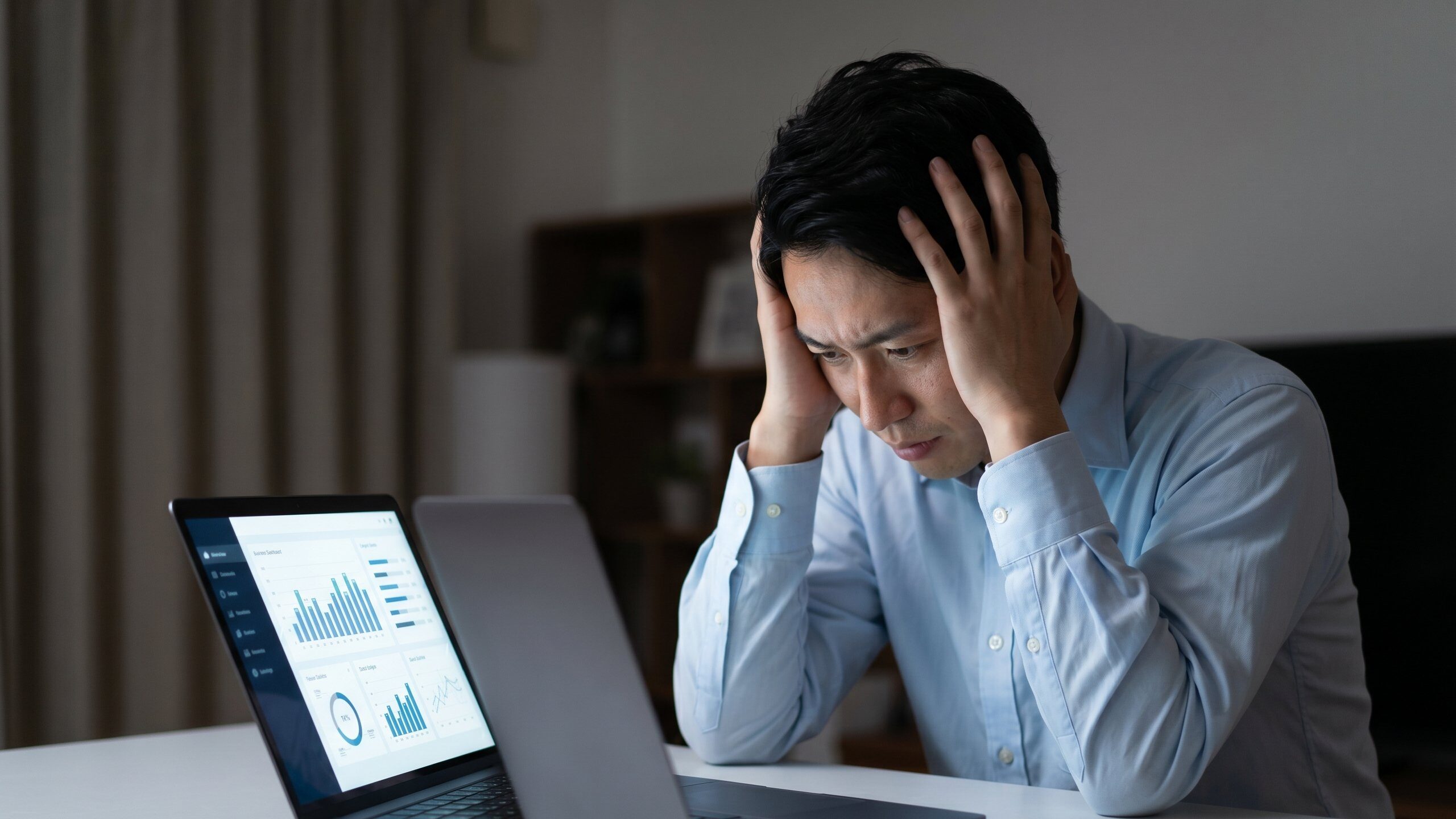 不動産売却で家が売れないストレスを解消するため、パソコンでデータ分析を行うものの、具体的な原因や対策が見つからず悩む男性。